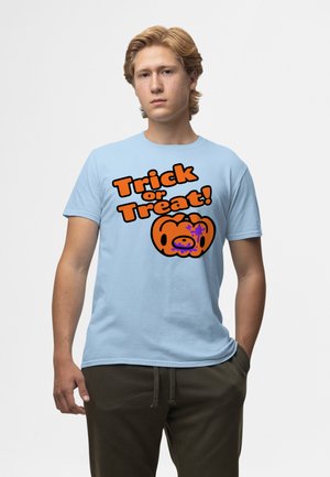 Ung mand iført en lyseblå T-shirt med orange tekst "Trick or Treat!" og en tegnet græskar grafisk på en hvid baggrund.