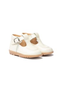 Zapatos de charol blancos con diseño de tira en T, cierre de hebilla y costuras decorativas. Suela de goma marrón con agarre texturizado.