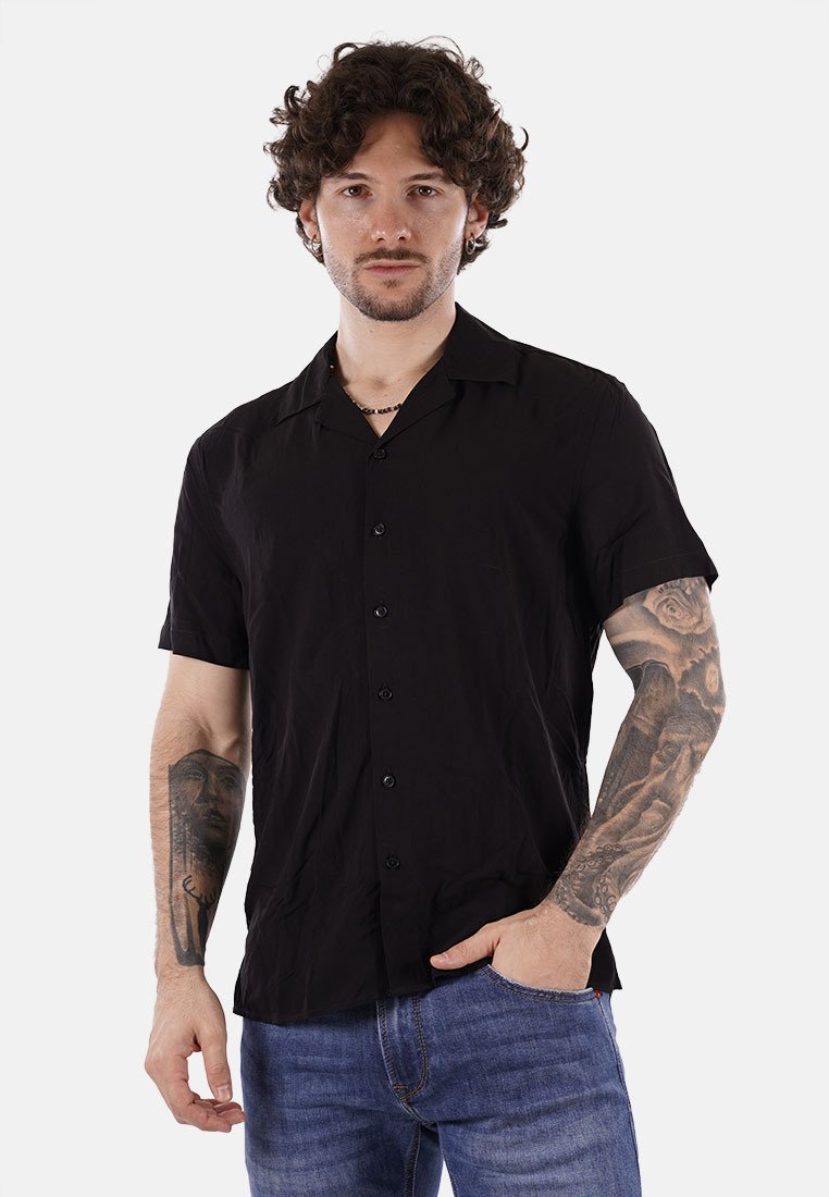 Camicia nera a maniche corte con bottoni, presenta una vestibilità ampia, un tessuto texturizzato e un colletto classico, abbinata a jeans in denim blu.