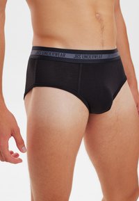 Sorte trusser lavet af et glat stof, med en grå elastik med "JBS UNDERWEAR" tekst. Afskåret stil med tætsiddende pasform og minimal detaljer.