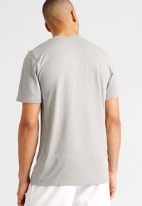 Grå t-shirt med kort ärm tillverkad av ett mjukt och lätt tyg. Har en rund halsringning och diskret sömnad vid fållen och ärmarna.