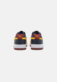 Puma sneakers with a navy, yellow, and burgundy color scheme, featuring a textured back panel, white midsole, and rubber outsole.