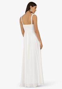 Weißes Maxikleid mit gerafftem Rücken, dünnen Trägern und einem fließenden Rock. Leichter Stoff mit einer glatten Textur.