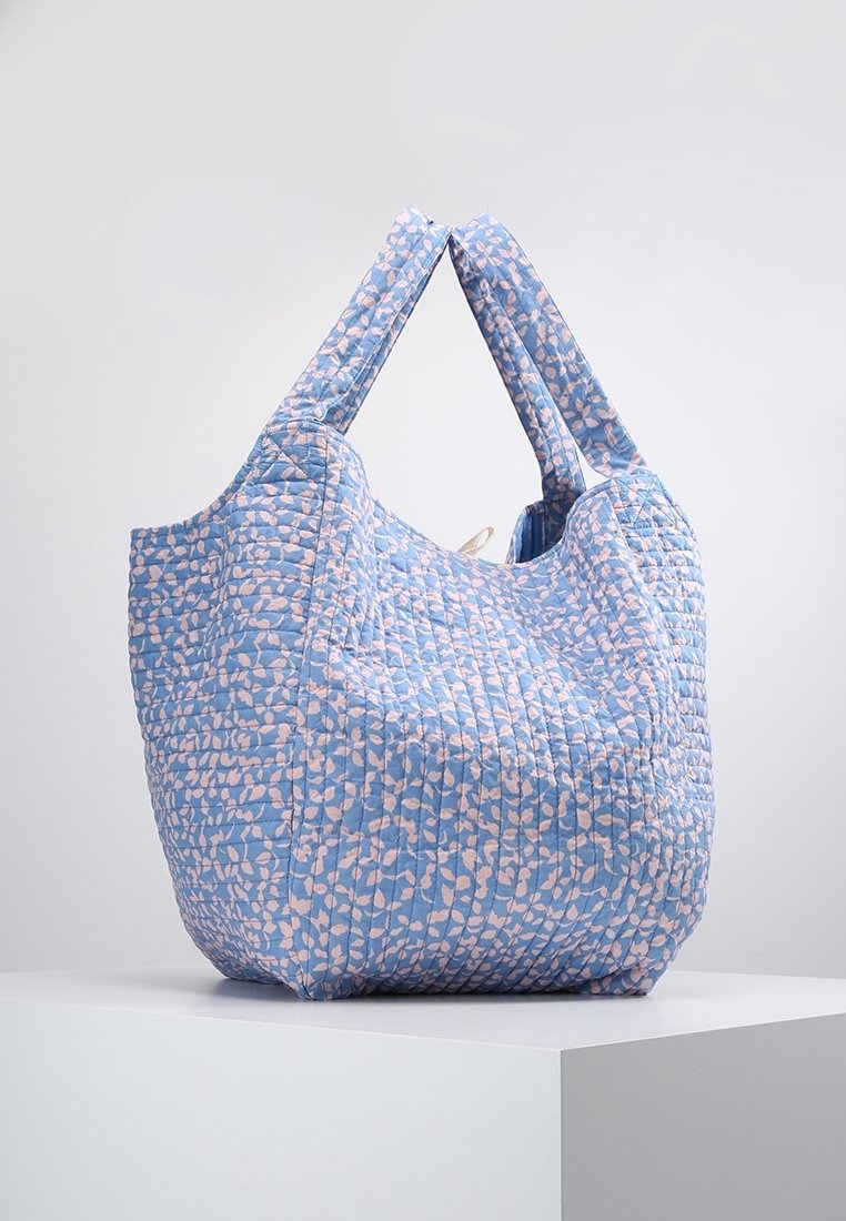 Sac cabas matelassé bleu avec un motif de feuilles roses. Dispose de deux poignées en tissu robustes et d'une large ouverture pour un accès facile.