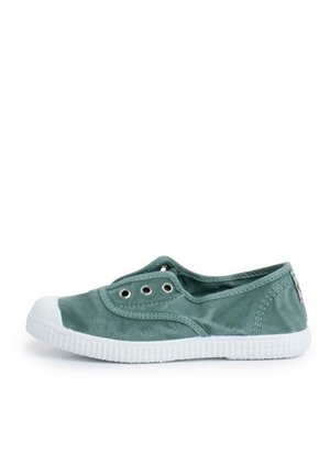 Grüner Canvas-Slipper mit weißer Gummisohle und Zehenkappe, Metallösen und niedrigem Schnitt.