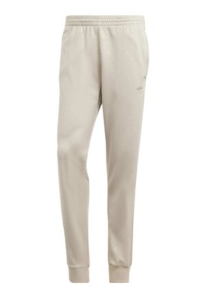 Jasnobeżowe zwężane spodnie dresowe z elastycznym pasem i ściągaczami, z subtelnym logo Adidas na górnej części uda.