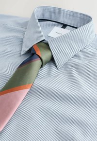 Gestreifte Herrenhemd in Hellblau mit einem taillierten Kragen; kombiniert mit einer mehrfarbigen gestreiften Krawatte in Grün, Marineblau und Pink.