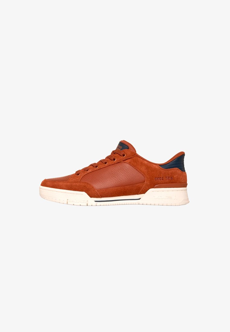 Baskets basses orange rouille avec empiècements en suède et cuir, détail noir à l'arrière, fermeture à lacets à l'avant et semelle texturée blanc cassé.