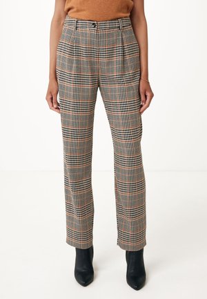 Femme portant un pantalon à carreaux taille haute beige, noir et orange, associé à des bottines noires pointues.
