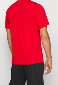 Rotes T-Shirt mit kurzen Ärmeln, Rundhalsausschnitt und einem glatten, leichten Stoff. Einfaches Design ohne sichtbare Muster oder Akzente.
