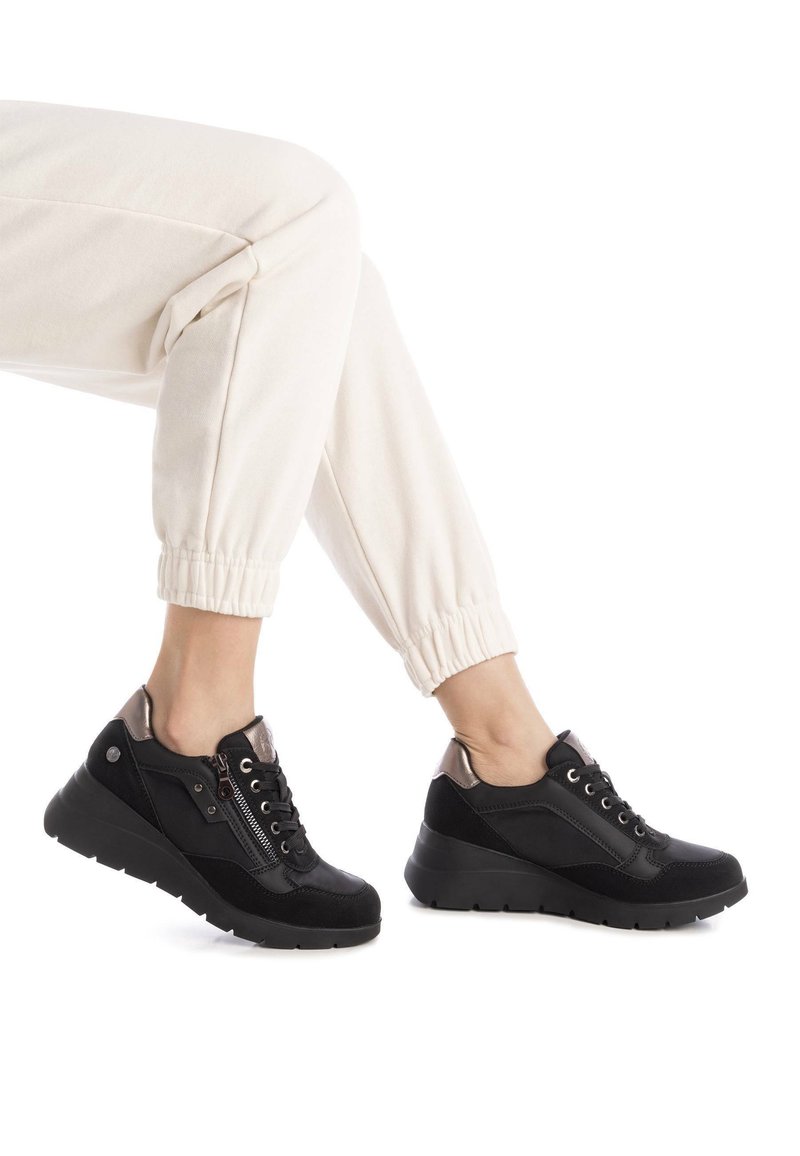 Zapatillas deportivas negras con una mezcla de cuero y ante, que presentan un detalle de cremallera, acentos texturizados y un diseño de suela gruesa.