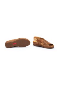 Sandalias de cuña de cuero marrón con diseño perforado. Presentan un acento trenzado alrededor de la suela y una suela de goma marrón texturizada.