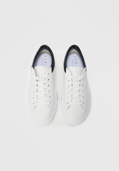 Pair of white low-top sneakers with black heel accents and white laces, viewed from above on a white background.