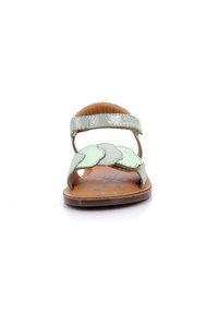Sandal de cuero verde menta con una correa brillante y detalles decorativos en forma de ondas. Diseño abierto con una plantilla de cuero marrón y estampado floral.