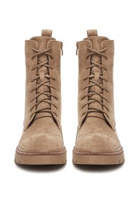 Cizme maro deschis din piele întoarsă, cu șireturi, gleznă înaltă, talpă groasă de cauciuc și cusături decorative de-a lungul marginii tălpii. Prevăzute cu bucle pentru a fi încălțate ușor.