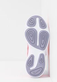 Czerwono-białe sneakersy z fakturowaną gumową podeszwą, z zakrzywionymi rowkami w kolorze szarym. Górna część ma gładką powierzchnię z minimalnymi akcentami.