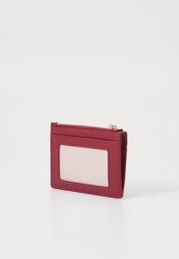 Portafoglio in pelle rossa con chiusura a zip, dotato di uno slot trasparente per l'ID sulla parte anteriore e dettagli cuciti lungo i bordi. Forma compatta e rettangolare.