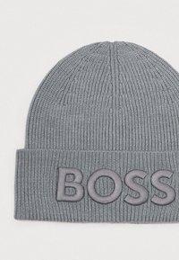 Sivá pletená čiapka s ryhovanou textúrou a prehnutým lemom, ktorý zobrazuje vyšívané logo "BOSS" v sivej farbe. Klasický okrúhly tvar.