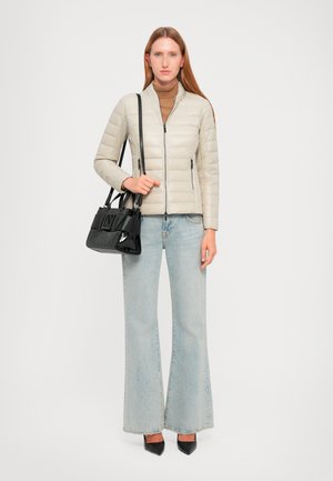 Chaqueta acolchada de puffer gris claro con cremallera frontal, cuello alto y bolsillos laterales; combinada con jeans de campana azul claro y un bolso negro.
