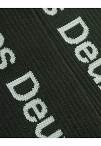 Tessuto lavorato a maglia verde scuro con dettagli in testo bianco. La texture è a coste, evidenziando il motivo delle lettere.
