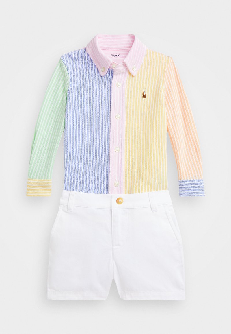 Chemise à manches longues rayée avec des couleurs vertes, bleues, roses, jaunes et blanches. Shorts blancs avec un bouton. Matériau en coton ; design décontracté.
