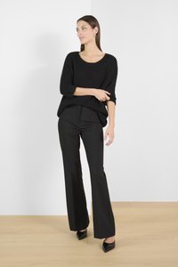 Sort strikket sweater med en afslappet pasform, rund udskæring og 3/4 ærmer. Sammen med tætsiddende sorte bukser og spidse hæle.