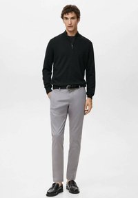 Musta vetoketjullinen neulepaita, vaaleanharmaat slim fit -housut, mustat loafersit. Neuleessa on resorikuvio, housuissa vyölenkit ja sivutaskut.