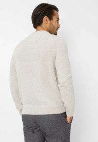 Helles graues Strickpullover mit geripptem Textur an den Schultern und Bündchen, ausgestattet mit einem runden Ausschnitt und geradem Saum. Trägt dazu eine dunkelgraue Hose.