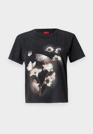 Svart bomull t-skjorte med et stort hvitt blomster- og sommerfuglgraphic på forsiden. Korte ermer og rund hals.