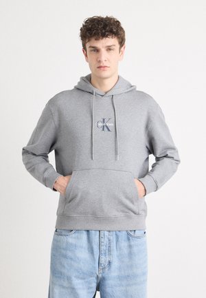Grijze sweatshirt met een capuchon, voorzien van een kangoeroezak en een Calvin Klein logo. Gemaakt van zachte stof met ribgebreide manchetten en onderkant.
