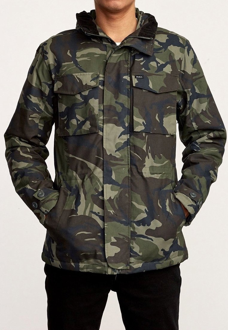 Veste à motif camouflage fabriquée dans un tissu résistant, dotée d'une fermeture éclair à l'avant, de poches à boutons et d'une capuche ajustable. Les couleurs incluent des verts foncés et des noirs.