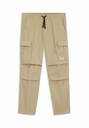 Pantaloni cargo beige con vita elastica e coulisse nera, caratterizzati da tasche con pattina laterali e una piccola etichetta bianca del marchio sulla tasca destra.