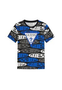 T-shirt à manches courtes en coton noir avec de grands motifs de logo "GUESS" en bleu, gris et blanc, et un accent de logo triangulaire central.