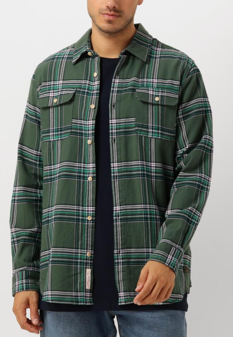 Camisa de franela a cuadros verdes con dos bolsillos frontales, botones de madera y corte relajado; presenta líneas blancas, grises y azules en el patrón.