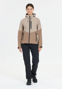 Women's waterproof jacket in beige and brown, featuring a hood, zippered front, and black accents. Smooth texture with structured design.