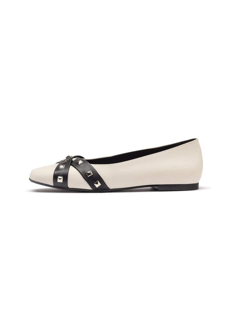 Scarpe flat in pelle color crema con cinturino incrociato nero decorato con borchie argento. Design con punta appuntita e tacco minimale.