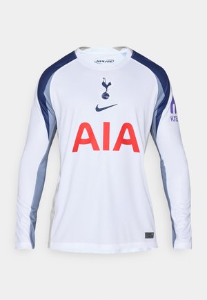 Balta garām piedurknēm futbola krekls ar tumši ziliem akcentiem, ar Tottenham Hotspur logotipu un "AIA" sarkanā krāsā uz priekša.