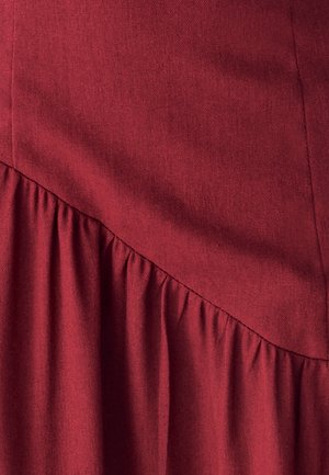 Nahaufnahme von strukturiertem rotem Stoff mit diagonaler Naht und gerafften Falten entlang der Nähte.