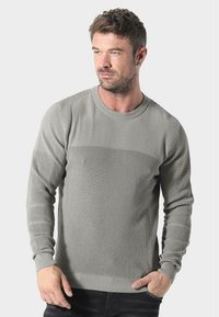 Grauer Strickpullover mit rundem Ausschnitt, strukturierten Rippmustern an Schultern und Ärmeln sowie engeren Bündchen.