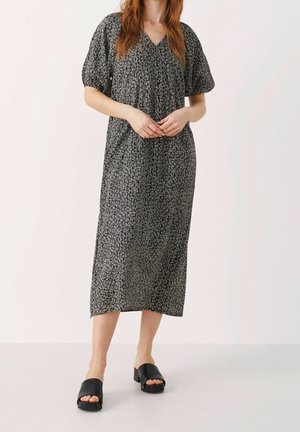 Robe mi-longue noire avec un imprimé abstrait blanc. Présente des manches courtes bouffantes et un décolleté en V. Assortie avec des sandales noires à enfiler.