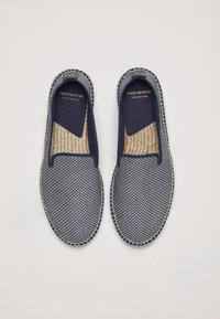 Baskets navy à enfiler avec un design en maille tissée, semelle de couleur claire et détails de couture. L'étiquette indique "FRED MARTIN, FABRIQUÉ EN ESPAGNE."