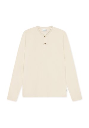 Maglietta henley a maniche lunghe color crema realizzata in tessuto testurizzato, con scollatura rotonda, patta con tre bottoni e orlo inferiore dritto.