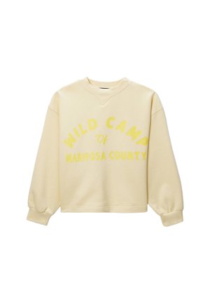 Sweatshirt oversized jaune-beige avec des manches larges. Présente l'inscription "WILD CAMP de MARIPOSA COUNTY" en lettres jaunes contrastantes et en gras.