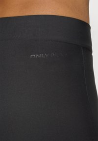 Crne tajice od glatkog, rastezljivog materijala. Imaju široki pojas i diskretni logo "ONLY PLAY" utisnut na vrhu.