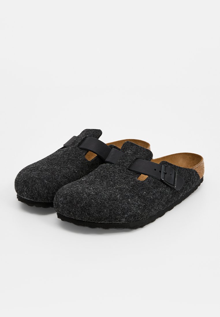 Dunkelgraue Filz-Schlupfschuhe mit schwarzem verstellbarem Schnallenriemen und Korkfußbett, seitliche Ansicht auf weißem Hintergrund.