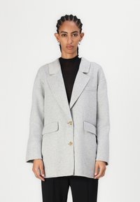 Blazer de lana gris claro con cuello de muesca, dos bolsillos frontales y cierre de un solo botón. Textura suave y corte relajado.