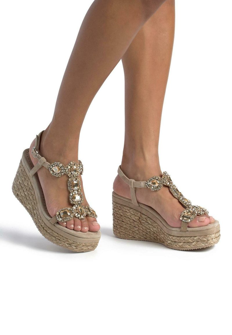 Sandali con tacco a cuneo beige, dotati di una suola in juta intrecciata e caratterizzati da una fascia decorativa ornata con gioielli trasparenti e in tonalità oro.