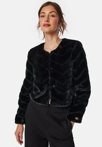 Zwarte nep bont cropped jack met een chevron patroon, ronde halslijn en drukknoopsluiting. Heeft een gestructureerde, zachte stof en logo-accent.