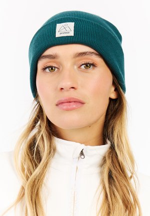 Teal geribde beanie met een vierkante logo patch met een bergontwerp. Zachte textuur, aansluitende vorm en casual stijl, geschikt voor koud weer.