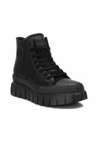 Zapatillas altas negras con suela de goma texturizada, detalle del logo redondo y cordones planos. Parte superior sintética suave con un diseño de plataforma gruesa.